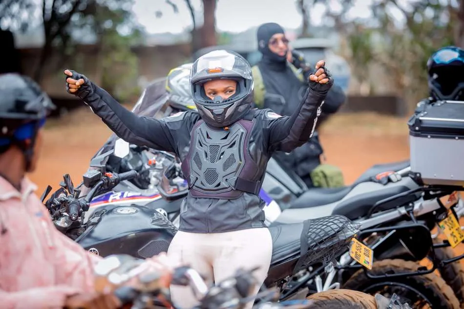 A rider in full protective gear flashing a peace sign