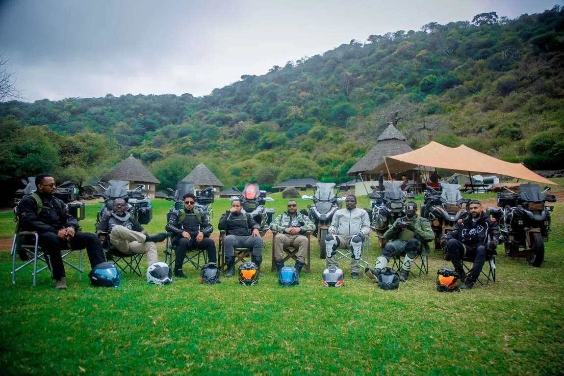 The crew seated in front of their motorcycles at camp